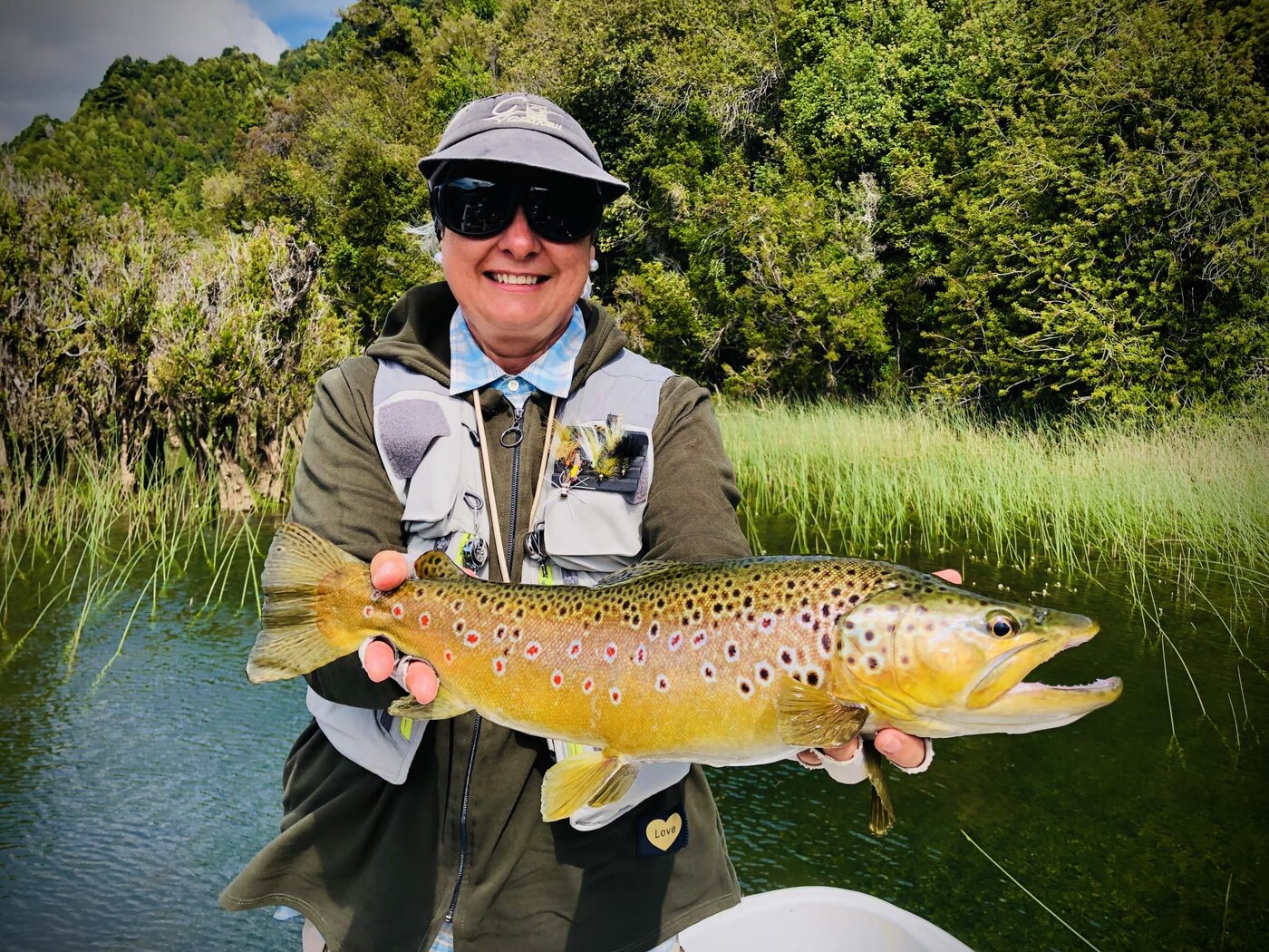Pescadora con trucha marrón en el lago